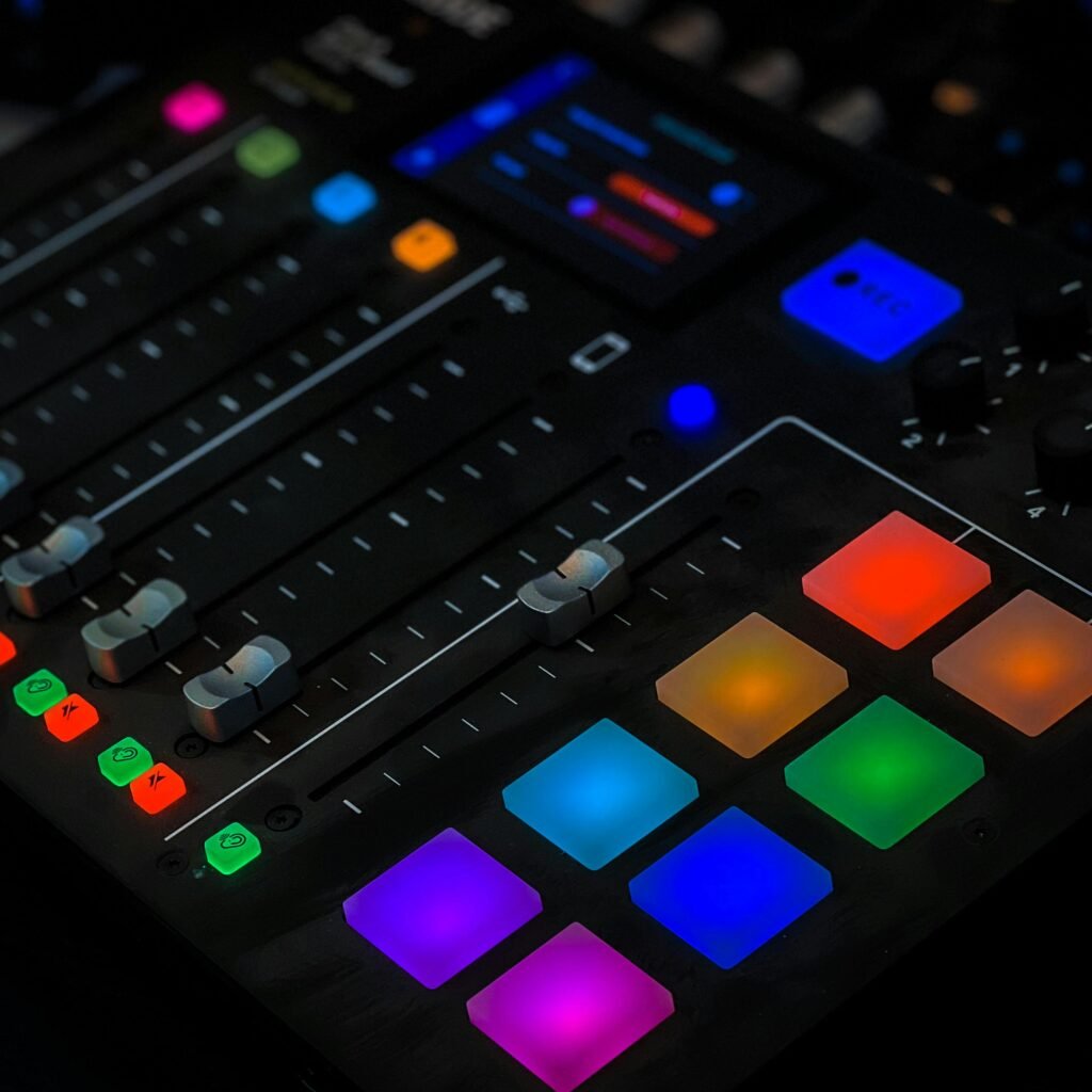 Close-up of a vibrant audio mixer with illuminated pads, showcasing modern sound technology in a studio setting.